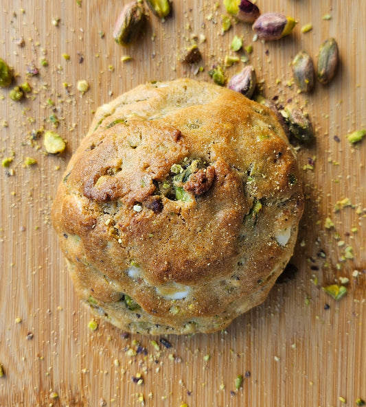 "Close-up of homemade pistachio cookies with a golden-brown crust. Stuffed with pistachio cream and toasted pistahios."